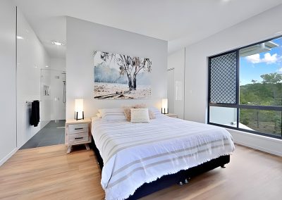 Bedroom with striped bedspread, gum tree artwork and large corner window