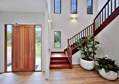 Entry with timber front door and timber staircase beside indoor plants