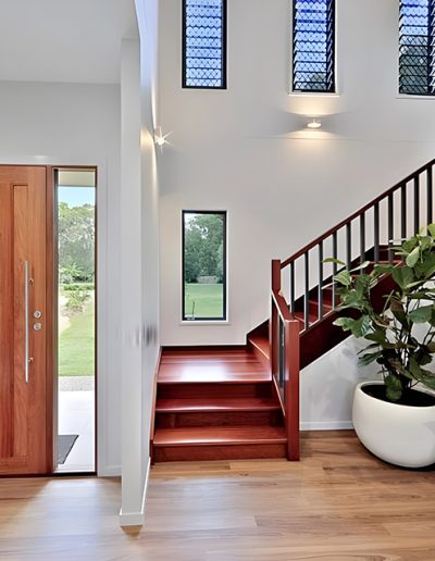 Entry with timber front door and timber staircase beside indoor plants