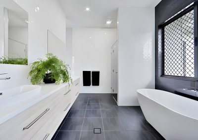 Bathroom with freestanding bath, long vanity and dark floor tiles