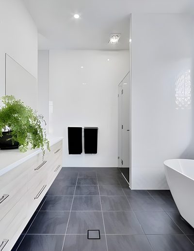 Bathroom with freestanding bath, long vanity and dark floor tiles