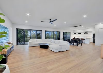 Large open-plan living room with white sectional sofa and timber-look floors