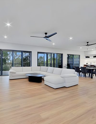 Large open-plan living room with white sectional sofa and timber-look floors