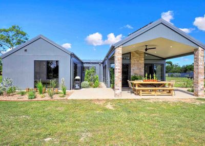 Grey-clad home with brick pillars and a covered outdoor dining area
