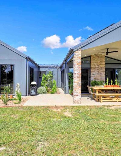 Grey-clad home with brick pillars and a covered outdoor dining area