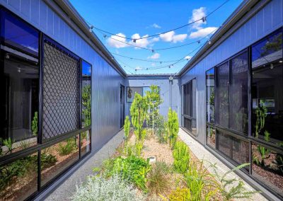 Internal courtyard garden between two dark-clad wings with festoon lights