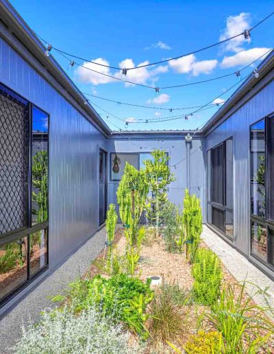 Internal courtyard garden between two dark-clad wings with festoon lights