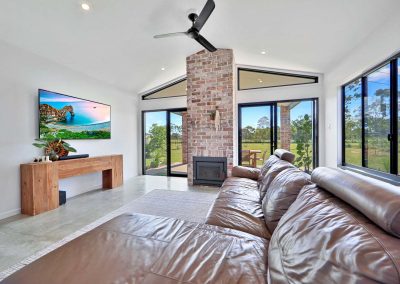 Living room with leather lounge, brick fireplace and raked ceiling