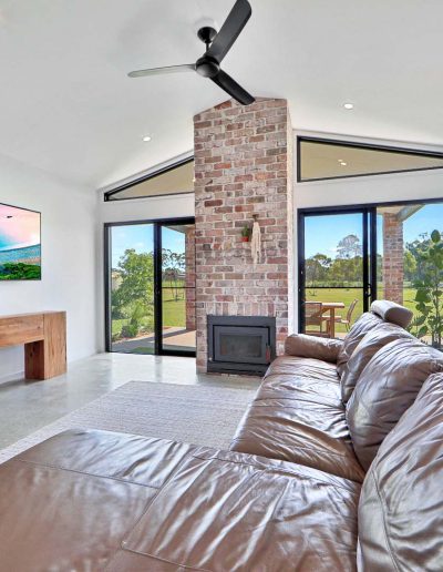 Living room with leather lounge, brick fireplace and raked ceiling