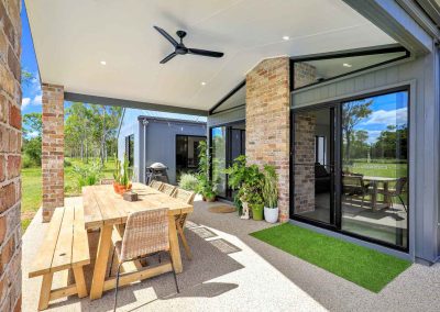 Covered alfresco with timber outdoor table, brick pillars and sliding glass doors