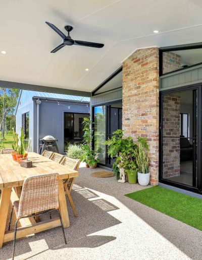 Covered alfresco with timber outdoor table, brick pillars and sliding glass doors