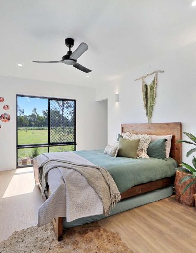 Bedroom with timber bed, green linen and a walk-in robe