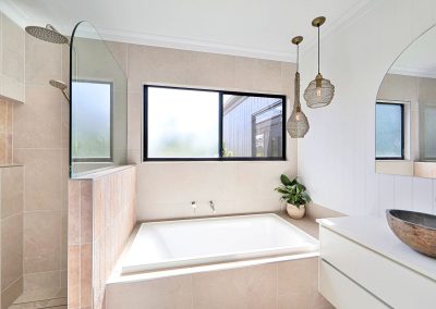 Bathroom with built-in bath under a window, pendant lights and stone basin