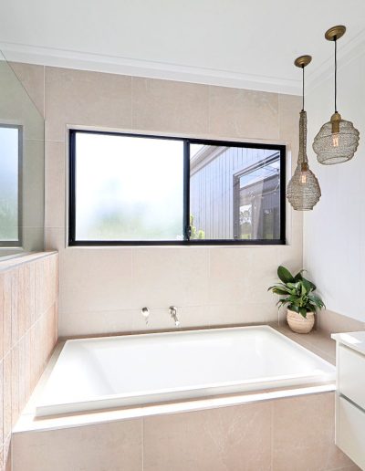Bathroom with built-in bath under a window, pendant lights and stone basin