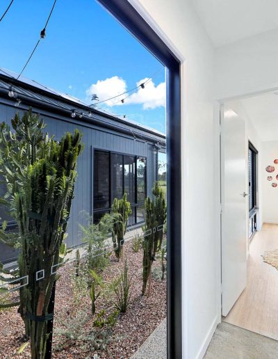 Courtyard garden seen through a full-height window beside a hallway