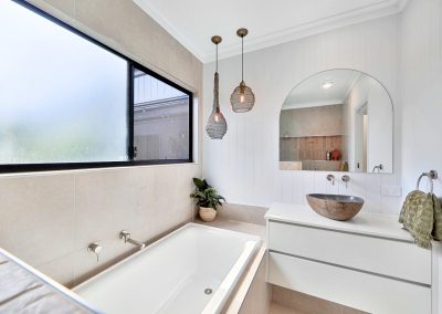 Built-in bath under a frosted window beside a stone basin vanity