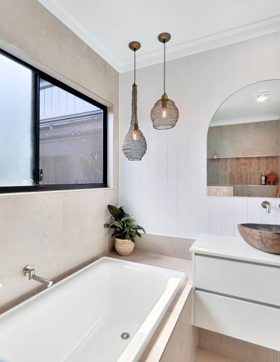 Built-in bath under a frosted window beside a stone basin vanity