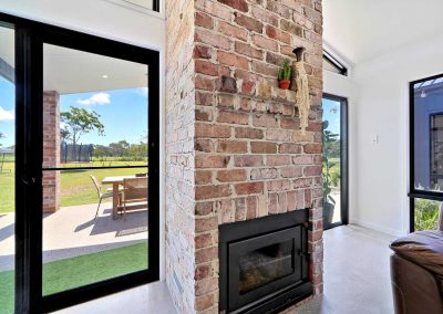 Brick fireplace beside glass doors opening to the alfresco