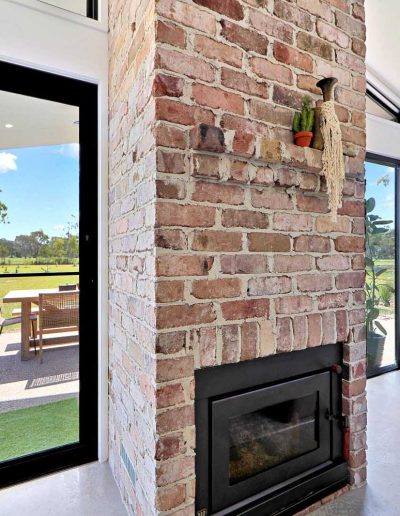 Brick fireplace beside glass doors opening to the alfresco