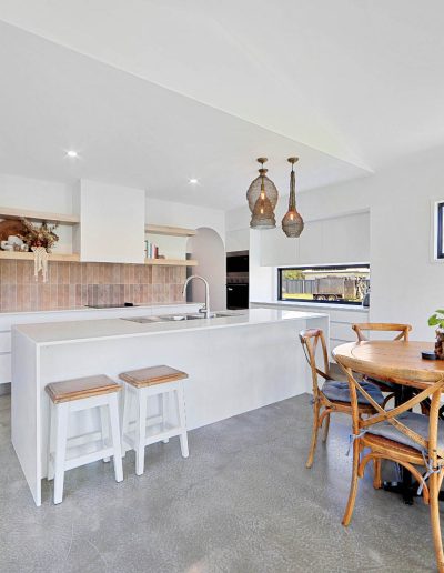 Kitchen bench with white stools beside a round timber dining table