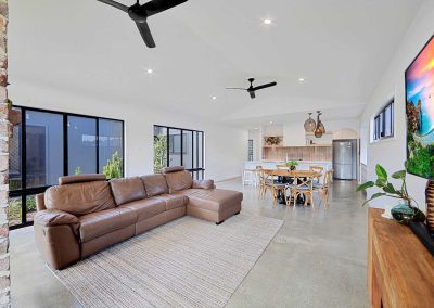 Open-plan living and dining with leather lounge and polished concrete floor