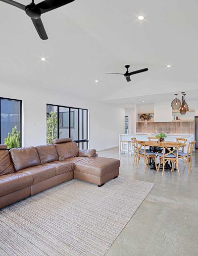 Open-plan living and dining with leather lounge and polished concrete floor