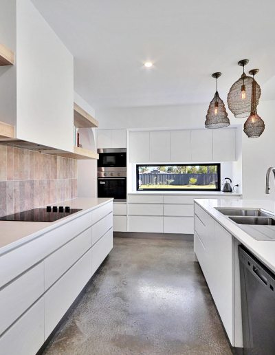 White kitchen with pink tile splashback, induction cooktop and woven pendant lights