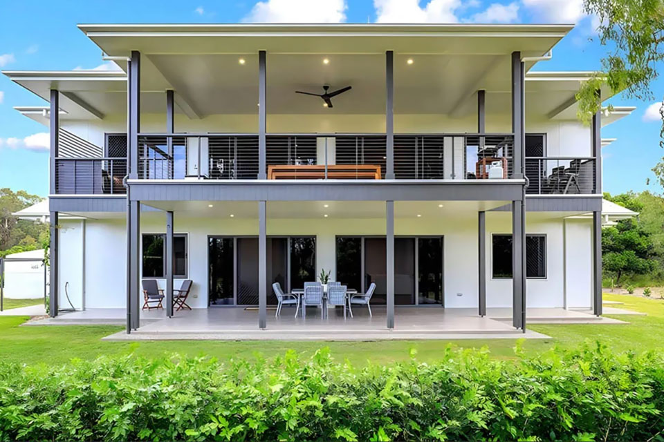 Two-storey home with wide covered decks and a hedge along the lawn