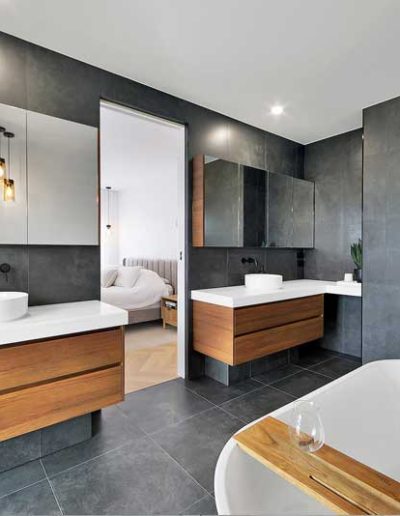 Dark-tiled bathroom with timber-look double vanity and freestanding bath