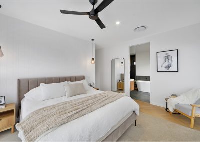 Bedroom with upholstered bedhead, cream linen and an ensuite with freestanding bath