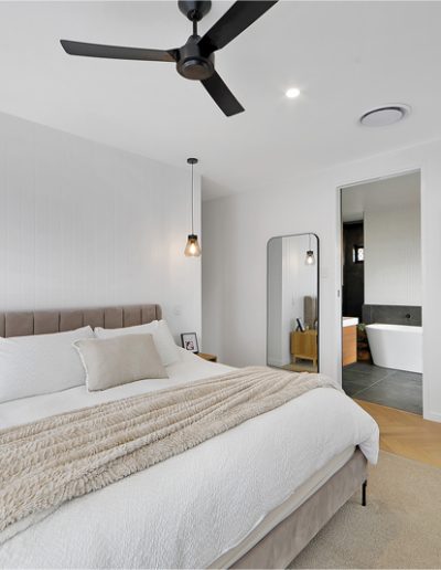 Bedroom with upholstered bedhead, cream linen and an ensuite with freestanding bath