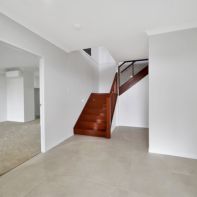 Tiled entry hall with a timber staircase and a carpeted room to the side