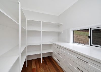 Walk-in pantry with white shelving, drawers and a window