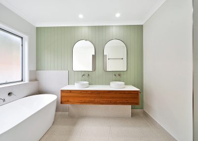 Bathroom with green panelled wall, double basins and timber vanity