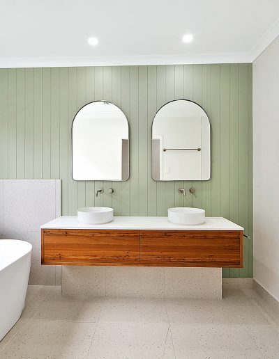 Bathroom with green panelled wall, double basins and timber vanity