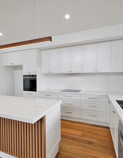 White kitchen with timber-slatted island and timber pendant light