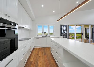 White kitchen with long island bench and a window over the sink