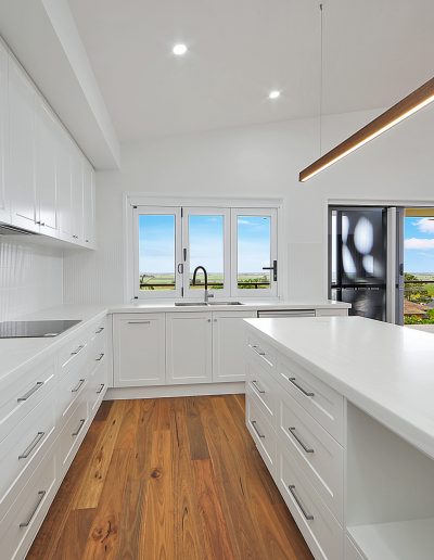 White kitchen with long island bench and a window over the sink