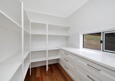 Walk-in pantry with open white shelves and a bank of drawers