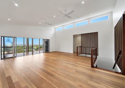 Living area with timber floors, high windows and slatted stair screen