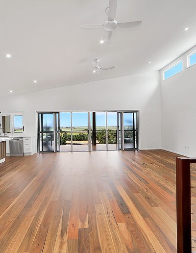 Open living area with timber floors and glass doors to a view