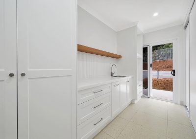 White cabinetry with sink, drawers and a floating timber shelf