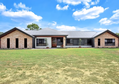 Single-storey brick and dark-clad home behind a large front lawn