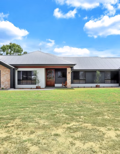 Single-storey brick and dark-clad home behind a large front lawn
